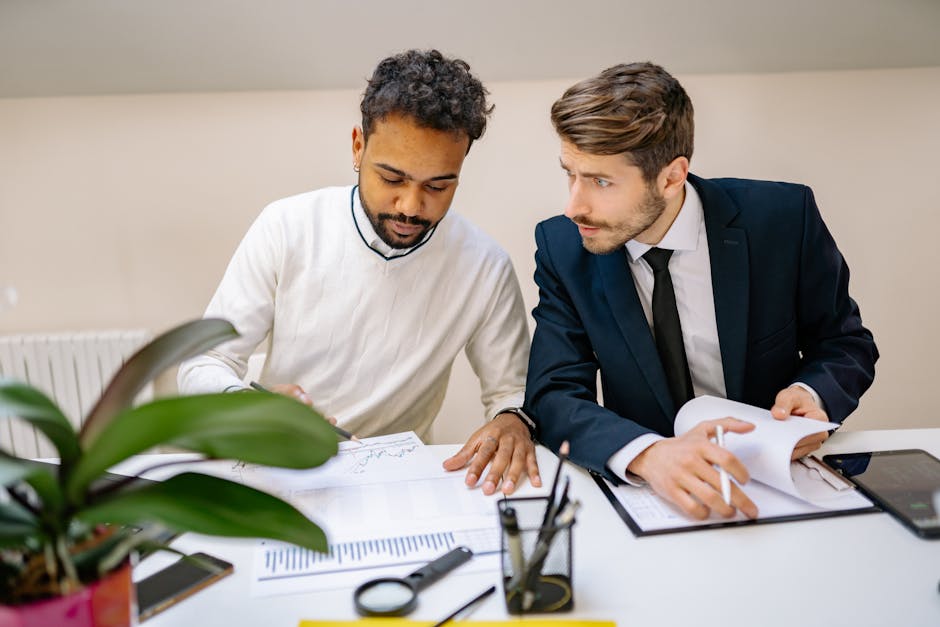 Two men in a modern office discussing and analyzing documents with charts.
